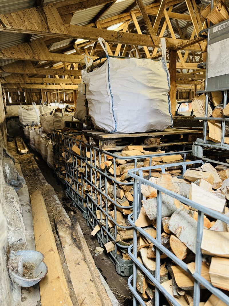 Wyvis seasoned firewood stored in IBC cages and bags inside a barn