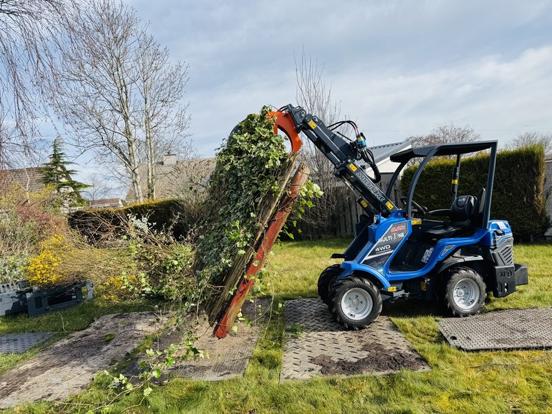 Multi One mini-loader removing dense ivy and brash from a domestic garden