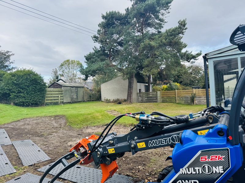 Multi One mini-loader on a tidied garden site beside a Scots pine