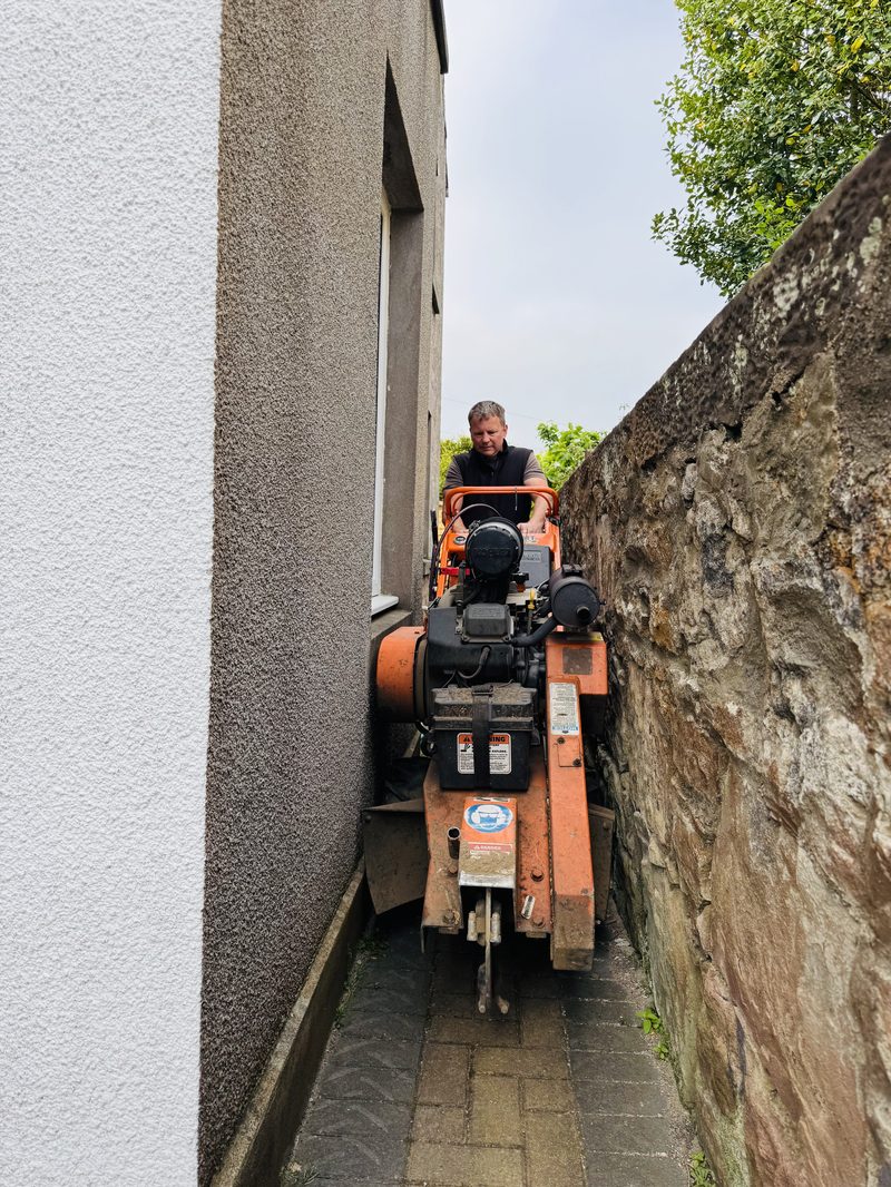 Stump grinder being walked through a narrow side passage