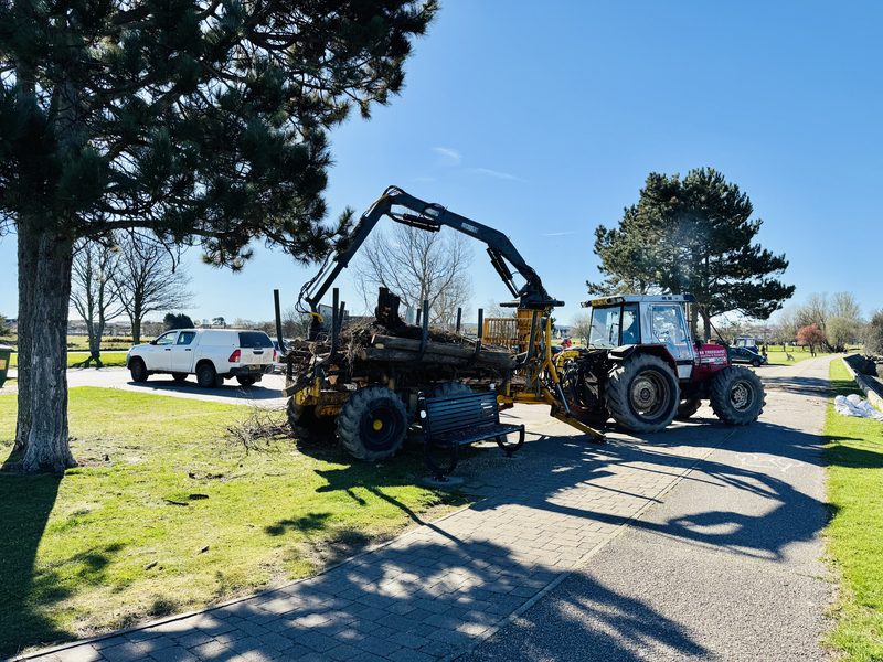Tractor with timber crane unloading roundwood logs
